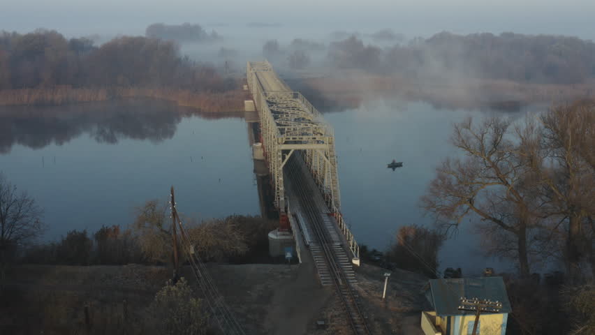 Aerial view of the railway bridge over the river in the fog in the early morning