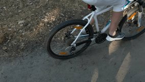 Bicycle wheels close-up while riding in the park. Mountain bike. Female legs in casual shoes riding a bicycle through the forest in summer. Ecological mode of transport. High quality 4k video