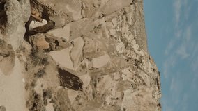 Vertical video. A young woman is sitting on ancient stones in the Turkish Valley of Imagination. Pano
