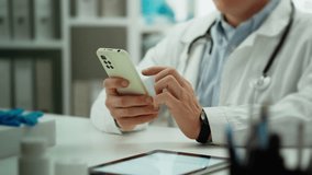 Doctor specialist in clinic uniform carefully works with modern telephone in doctor's waiting room. Camera movement middle aged man holding phone in hands modern consultation process, checking - Powered by Shutterstock - Get 15% off with code: PIKWIZARD15