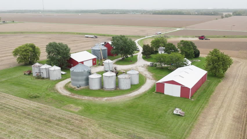 Aerial View of Farm with Silos, Barns, and Harvesting Machinery on Expansive Field Royalty-Free Stock Footage #1110151407