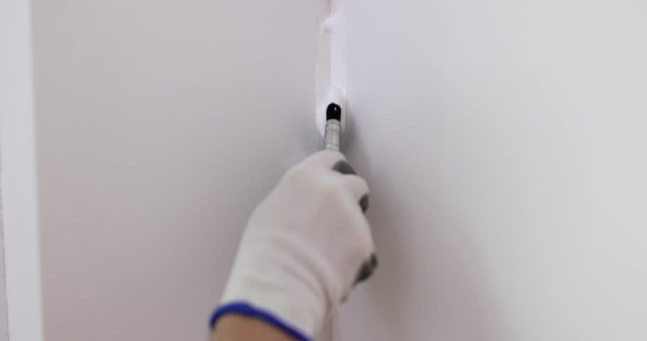 Craftsman paints seam in corner of wall in house with white brush. Painting, painting and plastering work Royalty-Free Stock Footage #1110157511