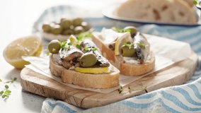 Sardines sandwiches with ciabatta bread, cream cheese and olives. Mediterranean food, stock video 4k