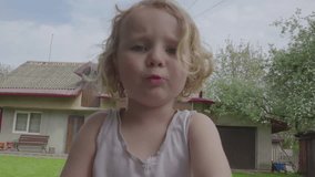 a little girl is talking to the camera,waving hands and pointing and talking close-up to the camera, shooting yourself on camera