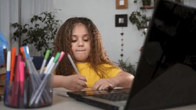 Home education concept.kid is studying online on a laptop at home. the child receives education at home online. video communication with teachers remotely. kid completes teacher's assignment remotely