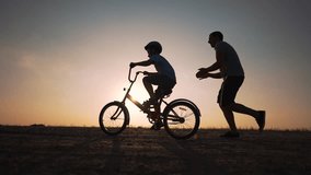 Father's Day. Father teaches son to ride bicycle wearing safety helmet. child learn to ride bicycle in park at sunset. Happy family concept and dream. Active father teaches child to ride bike in park - Powered by Shutterstock - Get 15% off with code: PIKWIZARD15