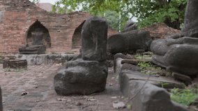 Buddha field of broken sculpture with beautiful ancient Buddha statue in middle of green nature, collection of old Buddha heads and busts covered with moss in Wat Umong temple in Chiang Mai, Thailand - Powered by Shutterstock - Get 15% off with code: PIKWIZARD15