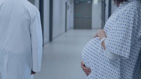 Fast moving clock over midsection of pregnant caucasian woman in hospital corridor. Pregnancy, healthcare, expectancy, time, development, motherhood and medical services digitally generated video.