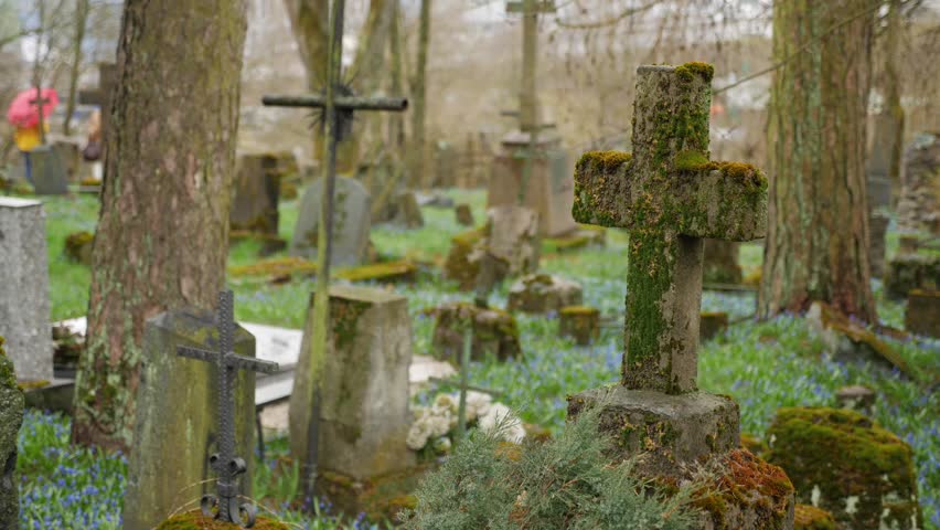 A peaceful old cemetery with a focus on a moss-covered cross Royalty-Free Stock Footage #1110176757