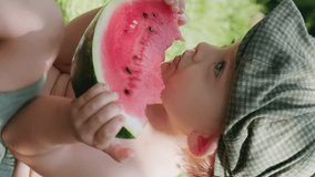 Vertical shot. Toddler boy eating watermelon enjoying summer. 