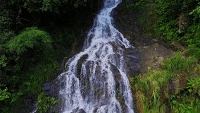 Waterfall flowing at cliff in the middle of tropical forest with aerial shot of drone shot.