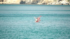 Aerial view of a family kayaking in calm blue sea. Unrecognizable woman and childrens. Kayak on turquoise sea water during warm day at sea. Summer holiday vacation and travel concept