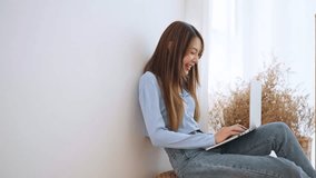 Young asian woman working at home. Happy female using computer laptop in living room at house