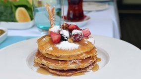 Syrup is poured over the pancakes. Stack of pancakes with strawberries, blackberries and maple syrup - Powered by Shutterstock - Get 15% off with code: PIKWIZARD15