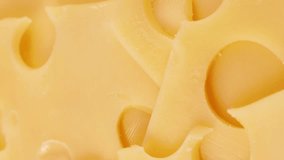 Vertical video format, Bright yellow maasdam cheese with large holes circle rotation close up
