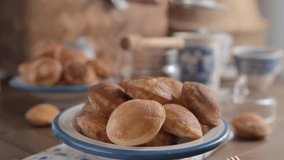  Close-up of golden Dutch Poffertjes with syrup and sugar. Delicious traditional mini pancakes on a plate.in the video, powdered sugar is poured onto mini pancakes in a white plate with a blue pattern