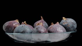 Figs in a glass bowl. They rotate on a black background, looped video, isolated.