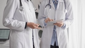 Two female doctors are using a tablet computer while standing and discussing health treatment in a hospital. Medicine concept