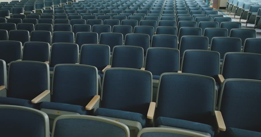 Overhead video of an empty renovated school theater, auditorium blue gray seats, chairs and new carpet in the aisle and luxury vinyl tile under the seats. Royalty-Free Stock Footage #1110209419