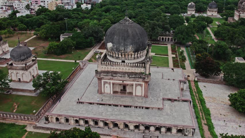 Qutub Shahi Tombs, hyderabad, telangana with crowded buildings and clouds at the background aerial establishing shot drone shot