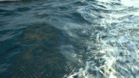 splashes and splashes with white foam from the boat movement on dark azure sea water, close-up view from above, material for video gluing, video transition, romantic overview video of yachting
