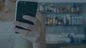 Animation of stock market data processing against mid section of woman using smartphone at a bar. Global economy and business data technology concept - Powered by Shutterstock - Get 15% off with code: PIKWIZARD15