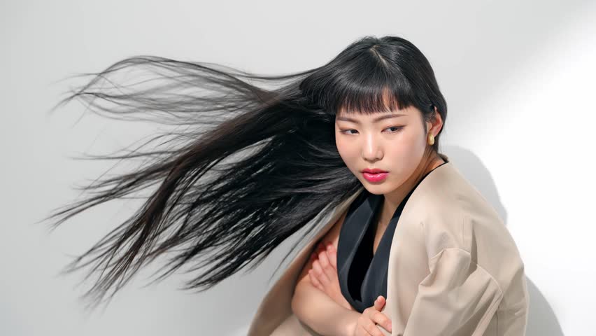Beautiful young Asian woman with long black hair blowing in the wind.  Hair care concept.