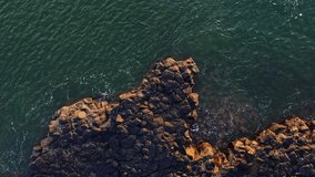 Rough volcanic lava rock rapids in the sea in the morning with aerial view. Landscape of sedimentary rocks and sea.
