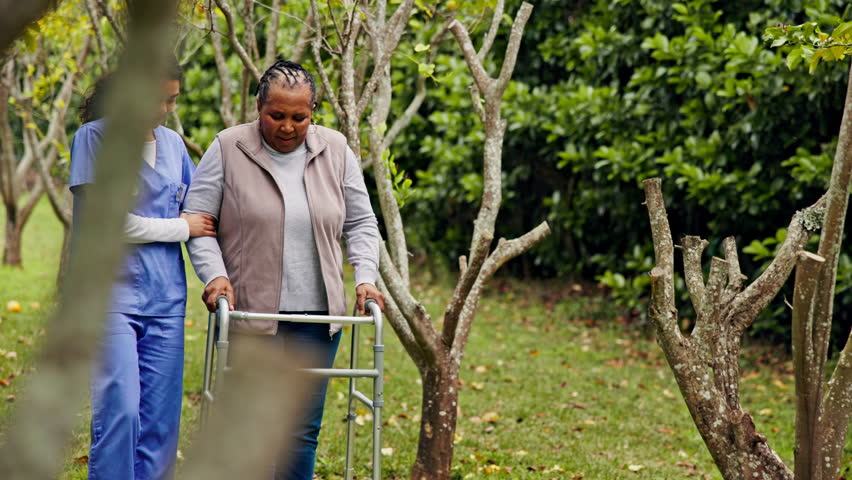 Retirement, old woman with walker and nurse in garden in support, help or trust at happy nursing home. Senior care, elderly person and caregiver walk with frame together with smile, trees and grass. Royalty-Free Stock Footage #1110220573