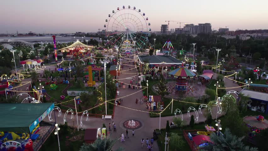 A drone flies over an amusement park with carousels and a Ferris wheel Royalty-Free Stock Footage #1110223627