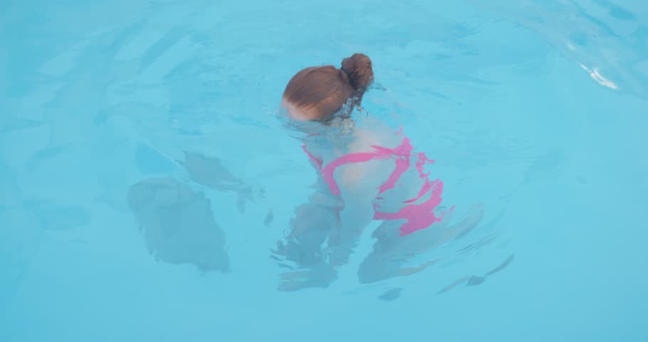 Young woman dressed in pink stylish swimsuit dives in to the crystal blue water. slim girl swims is under water. female sportswoman training in sport center, health care. lifestyle