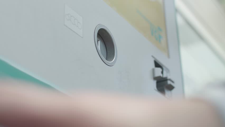 Hand of business person depositing coins into an ATM in Frankfurt, Germany