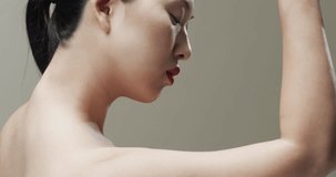 Asian woman with black hair, red lips and make up toching her face, copy space, slow motion. Health and beauty, make up, femininity concept, unaltered.