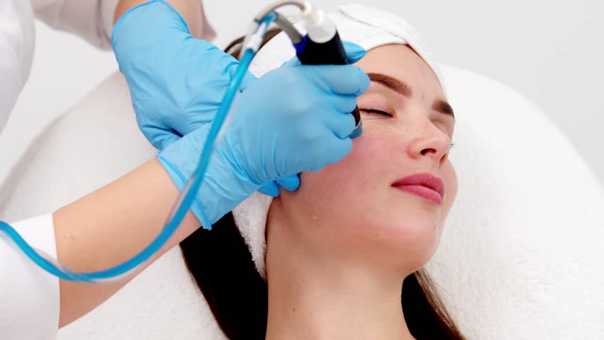 Professional female cosmetologist doing hydra-facial procedure in cosmetology clinic. Doctor using hydra vacuum cleaner. Rejuvenation and cosmetology concept Royalty-Free Stock Footage #1110240495