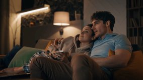 Smiling spouses watching tv sitting at cozy living room interior with coffee late evening. Happy married couple laughing enjoying funny show together at home. Lovely family leisure weekend concept. - Powered by Shutterstock - Get 15% off with code: PIKWIZARD15