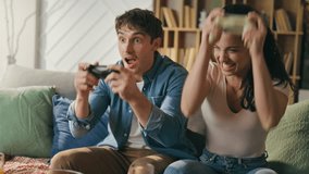 Video Gaming couple having fun together sitting cozy apartment sofa close up. Confused husband surprised by professional playing smiling wife. Laughing girlfriend rejoicing win video game competition. - Powered by Shutterstock - Get 15% off with code: PIKWIZARD15