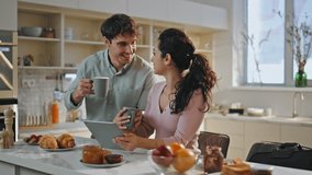 Married couple surfing internet having breakfast on cozy kitchen closeup. Happy spouses browsing online on tablet drinking coffee at comfortable cuisine together. Family morning with modern technology - Powered by Shutterstock - Get 15% off with code: PIKWIZARD15