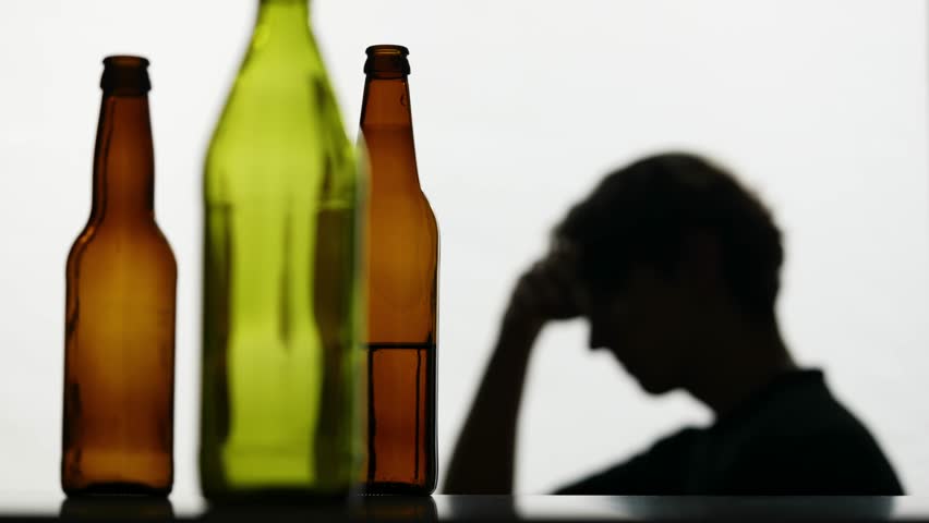 In the close-up shot, there are empty, broken glass bottles full of alcohol. In the background, the man is strong he is very sad, sad, sad. Demonstrates the struggle with addiction. Royalty-Free Stock Footage #1110248667