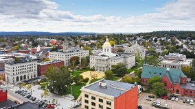 Aerial establishing shot of Concord with slow forward motion past New Hampshire State House golden dome. The capitol houses the New Hampshire General Court, Governor, and Executive Council.