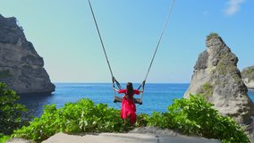 4K slow motion video of a woman sitting on a swing at Diamond Beach at Nusa Penida Island, Bali in Indonesia.