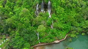Aerial Paradise: Explore a lush, hidden triple waterfall oasis in the heart of a tropical rainforest. Cascading waters glisten, surrounded by vibrant greenery, a secret gem from above. Thailand.

