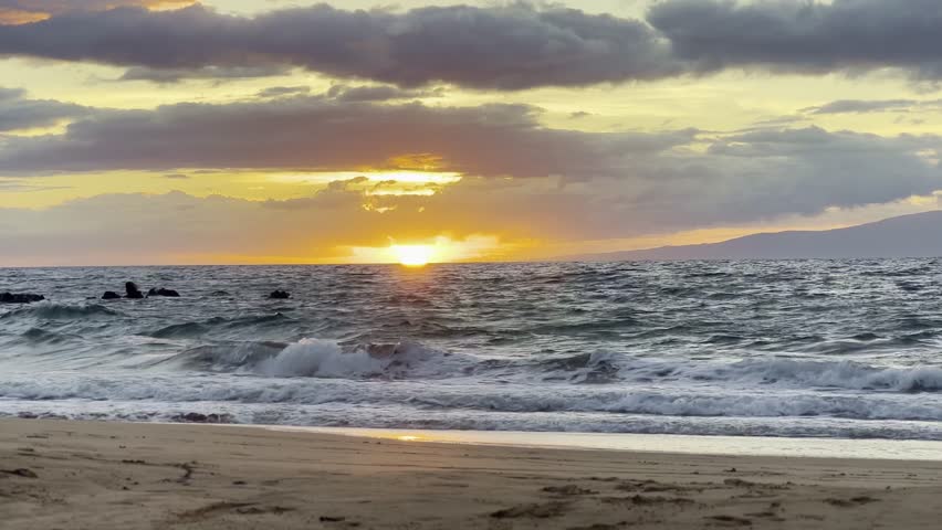 Cinematic wide shot of the sun setting over the horizon from Wailea Beach in South Maui, Hawai'i. 4K HDR at 30 FPS Royalty-Free Stock Footage #1110258701