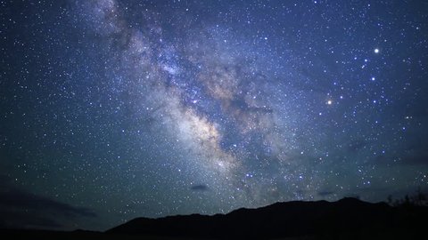 motion controlled astrophotography time lapse footage with dolly down, tilt down & pan right motion of Milky Way galaxy over desert landscape through dawn in Death Valley National Park, California