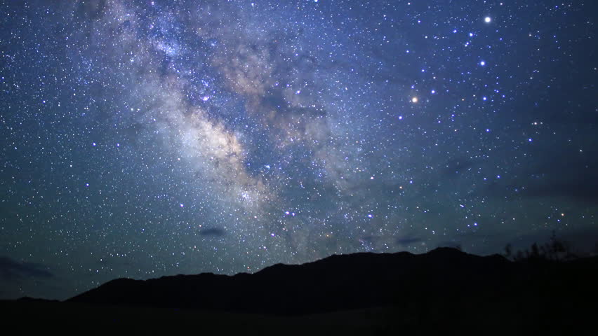 motion controlled astrophotography timelapse footage with dolly down, tilt down & pan right of Milky Way galaxy over desert landscape through dawn in Death Valley National Park, California -Long Shot-