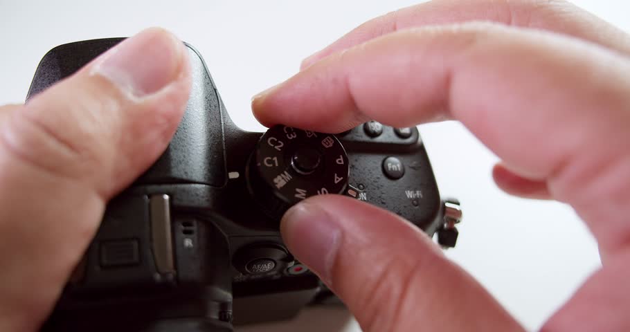 Turning the dial and pressing the buttons of the camera to adjust the settings before taking a photograph.