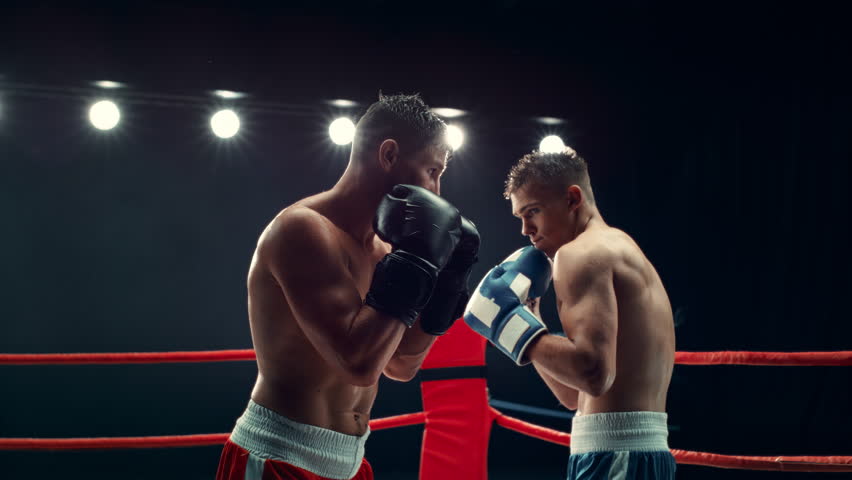 Cinematic Footage with a Speed Ramp Super Slow Motion Effect. Two Professional Boxers Fight in a Ring. Boxer Ducking to Avoiding a Hit, Punching with a Hook to the Face, Rocking the Opponent Royalty-Free Stock Footage #1110269875