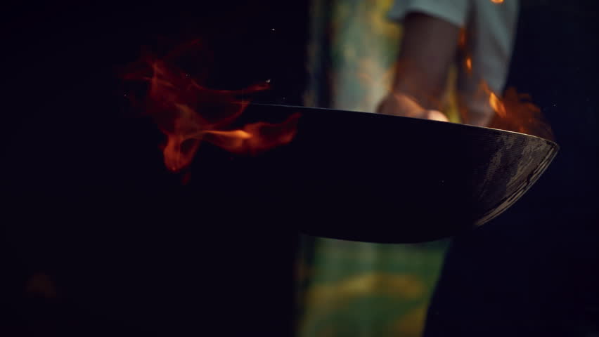 Chef Stir Frying Vegetables in a Flaming Wok in an Outdoors Kitchen. Person Cooking Food Using a Flambe Technique, Igniting Hot Oil and Alcohol in a Pan. Close Up Super Slow Motion Footage Royalty-Free Stock Footage #1110269959