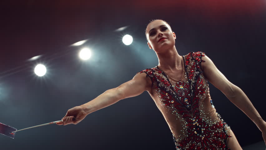 Portrait of a Graceful Rhythmic Gymnast Performing a Dance with a Red Ribbon. Young Female Exercising in a Striking Beautiful Uniform in a Dark Studio. Cinematic Super Slow Motion Speed Ramp Footage Royalty-Free Stock Footage #1110270003