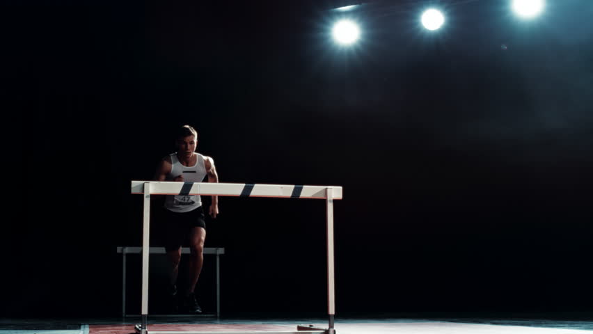 Strong Male Athlete is Running Towards an Obstacle, Hurdling, Jumping Over the Barrier at High Speed while Sprinting in a Race. Cinematic Super Slow Motion Footage with Speed Ramp Effect Royalty-Free Stock Footage #1110270023