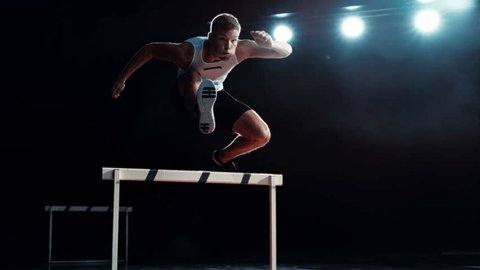 Strong Male Athlete is Running Towards an Obstacle, Hurdling, Jumping Over the Barrier at High Speed while Sprinting in a Race. Cinematic Super Slow Motion Footage with Speed Ramp Effect Stock-video